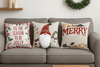 Grijze bank met drie kerstkussens met teksten en kabouter, krans aan muur, warme en knusse kerstsfeer in woonkamer