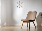 Metalen ster wanddecoratie met pijlen boven een moderne stoel in een lichte woonkamer